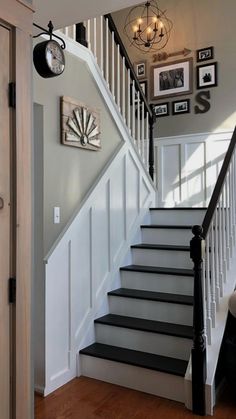 a staircase with pictures on the wall above it and a clock mounted to the wall