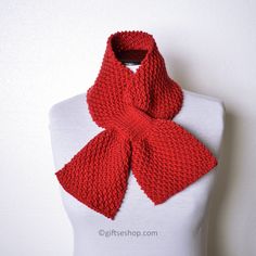 a red knitted scarf sitting on top of a white mannequin