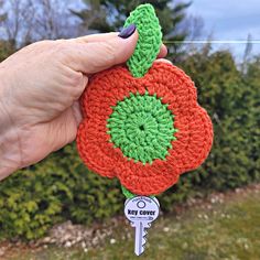 a crocheted key fob with a flower on it is held in someone's hand