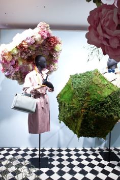 two mannequins with flowers on their heads in front of a green ball