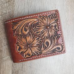 100% handmade bi-fold wallet made from leather. Wallet features floral tooling consisting of 4 flowers: 2 on front flap, 2 on back flap. Wallet has a dyed background to make the tooling stand out even more. INTERIOR OPTIONS: Money Clip has a metal Money clip for your cash and 6 card slots. Cash Slot A has a slot for your cash and 4 card slots. Cash Slot B has a slot for your cash and 6 card slots as well as a hidden pocket behind the cards for receipts and things. Initials can be added to the wallet. Write the initials in the message box.  Please allow 4-6 weeks for orders to be made and shipped.  If you have any questions send me a message and I will be glad to help. Hand Tooled Bifold Wallet, Brown Bifold Wallet With Leather Patch, Artisan Hand Tooled Leather Trifold Wallet, Artisan Hand Tooled Bifold Wallet, Brown Hand Tooled Trifold Wallet, Custom Brown Hand Tooled Wallets, Custom Hand Tooled Brown Wallet, Western Style Brown Trifold Wallet With Card Slots, Artisan Hand-tooled Bifold Wallet