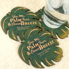 four palm tree coasters sitting on top of a white counter next to a bottle of water