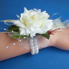 a white rose and pearls corsage on a woman's arm