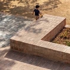 a young boy is walking up the stairs in front of a building that has been constructed out of bricks