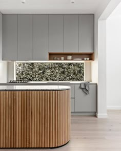 a kitchen with grey cabinets and an island countertop in front of a window that has plants growing on it