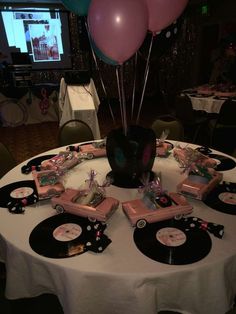 a table topped with lots of black and white plates covered in pink and purple balloons