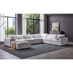 a living room with a large white sectional couch in front of a window and rug on the floor