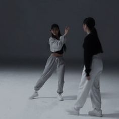 two people standing in the middle of a white room, one holding her arms out