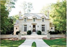 a large white house with lots of windows and bushes around the front door, on a sunny day