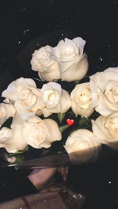 a bunch of white roses sitting on top of a glass table with water droplets around them