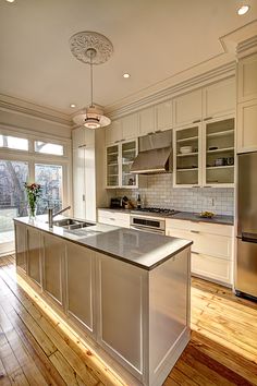 a large kitchen with an island and stainless steel appliances in the center, along with hardwood flooring