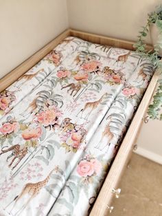 a baby crib with a flowered sheet and giraffes on it