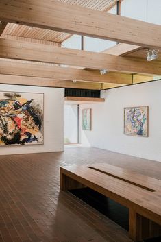 an empty room with wooden benches and paintings on the wall