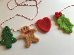 three felt ornaments hanging on a string with red and green decorations next to them,