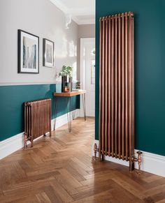 a wooden radiator next to a green wall in a room with hardwood floors