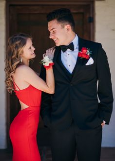 a man in a tuxedo standing next to a woman in a red dress