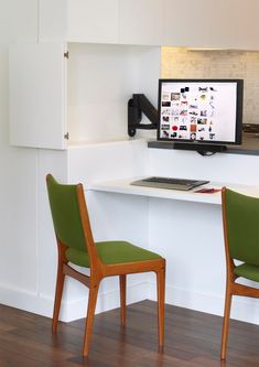 two green chairs sitting in front of a computer monitor on a wall above a desk