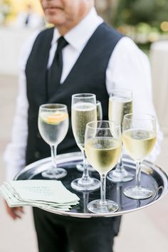 a waiter holding a tray with wine glasses on it