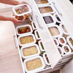 two hands reaching for food in containers on a counter top with drawers and dividers