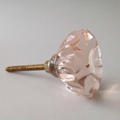 a close up of a pink glass object on a white surface with a gold screw