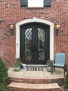 a black double door with two chairs in front of it and brick steps leading up to the entrance