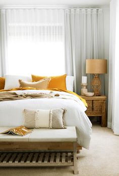 a bed with white sheets and yellow pillows