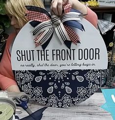 a woman sitting at a table with a sign that says, shut the front door