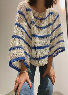 a woman is standing in front of a mirror with her hand on her hip, wearing a blue and white striped sweater