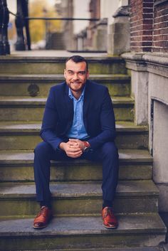 a man sitting on steps in front of a building wearing a blue suit and red shoes