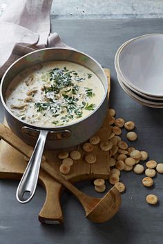 a pan filled with soup sitting on top of a wooden cutting board next to some crackers