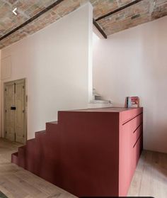 a room that has some stairs and a red cabinet in the corner with books on it