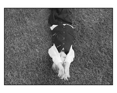 a black and white photo of someone's feet in the grass with their jacket on