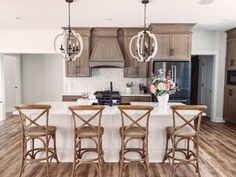 a large kitchen with wooden floors and white counter tops, along with an island in the middle