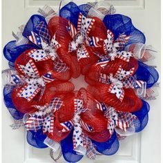 a red, white and blue mesh wreath on a front door with the american flag