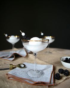 two martini glasses with blackberries in them on a table