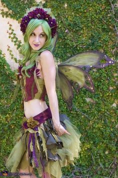 a woman dressed as a fairy standing in front of a wall