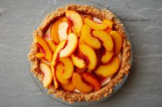 a pie topped with sliced peaches on top of a table