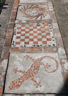 a lizard is painted on the sidewalk next to a brick walkway that has been made into a mosaic