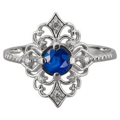 an oval blue sapphire and diamond ring with filigrees on the sides, set in 18k white gold