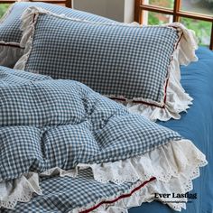 a bed with blue and white checkered sheets, pillows and ruffles on it