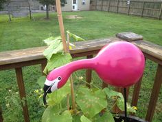 a pink flamingo planter sitting on top of a wooden fence