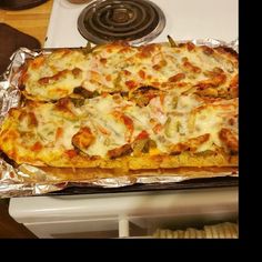 a pizza sitting on top of a pan covered in cheese and toppings next to a stove