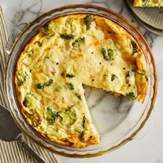 a quiche with broccoli and cheese is on a plate next to a fork