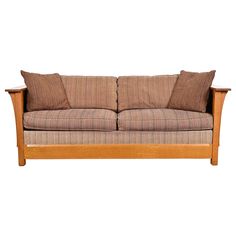 a wooden couch with two pillows on it's back and one arm folded down