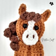 a crocheted brown and white horse with black eyes sitting on a white surface