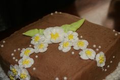 a chocolate cake with white and yellow flowers on it