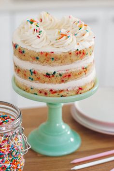 a cake with white frosting and sprinkles sitting on a green plate