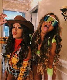 two women dressed up in costumes and hats posing for the camera with their tongue out