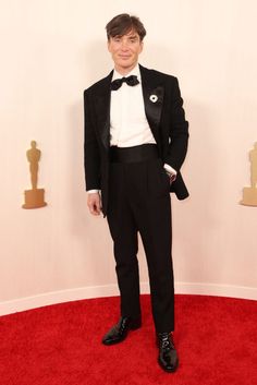 a man in a tuxedo standing on a red carpet