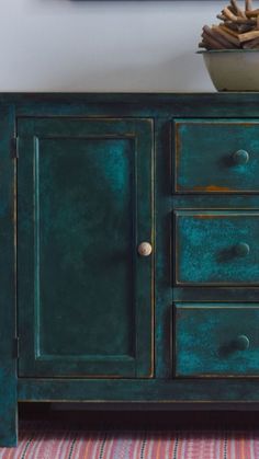 a green cabinet with drawers and a bowl on top